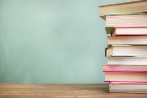 textbooks stacked on school desk with chalkboard background.